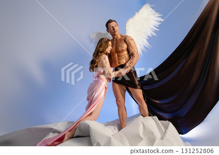 Couple poses together with angel wings against a colorful backdrop 131252806