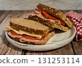 Ham, tomato and cheese sandwiches on seeded bread on light blue table 131253114
