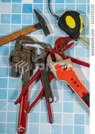 Essential plumbing tools lying on blue bathroom tiles ready for home improvement Essential plumbing tools lying on blue bathroom tiles ready for home improvement 131253120
