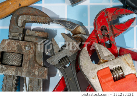 Adjustable wrenches and pipe wrench laying on blue tiles Adjustable wrenches and pipe wrench laying on blue tiles 131253121