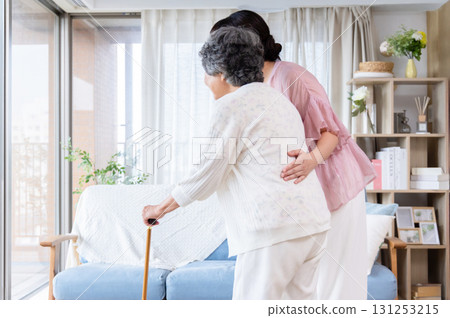 A young woman assisting a senior woman using a cane A young woman assisting a senior woman using a cane 131253215