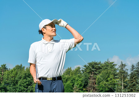 Male golfer looking up at the sky on the golf course Male golfer looking up at the sky on the golf course 131253302