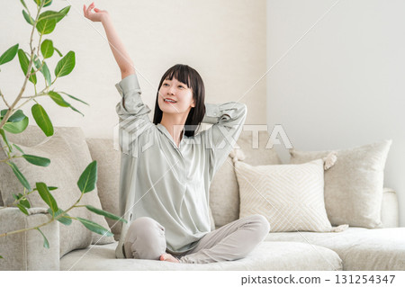 Young Asian woman relaxing and refreshing on the sofa at home (morning routine) Young Asian woman relaxing and refreshing on the sofa at home (morning routine) 131254347