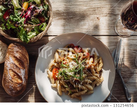 木桌上的義大利麵、麵包、沙拉和葡萄酒 131254656