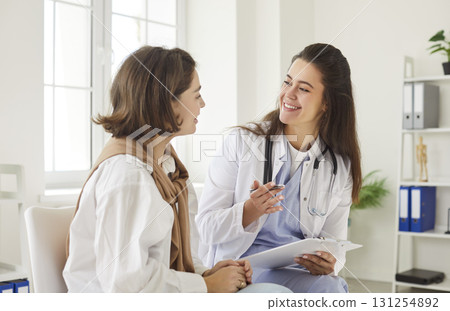 Professional help, positive young female practitioner doctor in clinic talking to woman patient 131254892