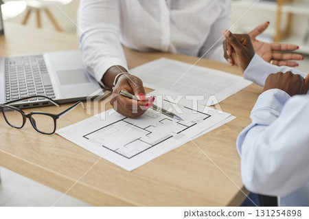 Young interior designer african american woman showing her client floor plan of new house. 131254898