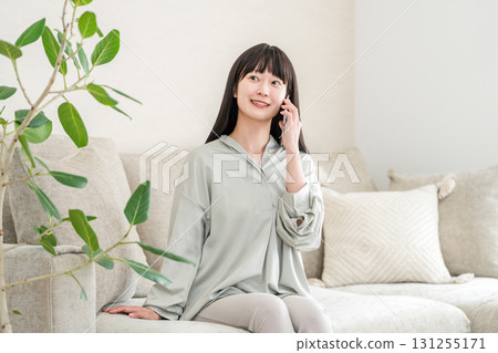 Japanese woman calling on smartphone (house, sofa, smile) 131255171