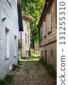 Narrow Alleyway Between Old Rustic Houses with Overgrown Path 131255310