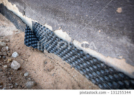 Damaged Foundation Waterproofing Membrane on Building Wall Closeup 131255344