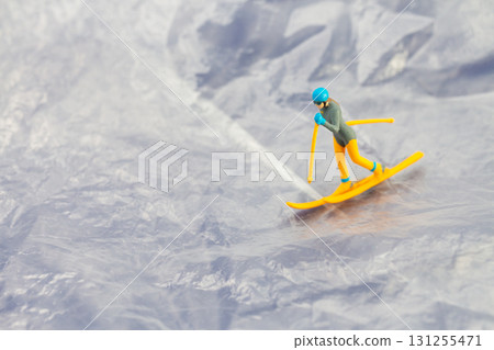 Creative concept image of a tiny figurine skiing down a snowy mountain landscape Creative concept image of a tiny figurine skiing down a snowy mountain landscape 131255471