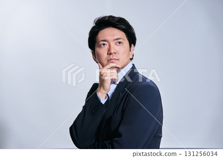 雄心勃勃的男經理，手托著下巴，在白色背景前思考 131256034