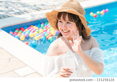 戴著草帽的亞洲年輕女子在泳池邊揮手 戴著草帽的亞洲年輕女子在泳池邊揮手 131256128