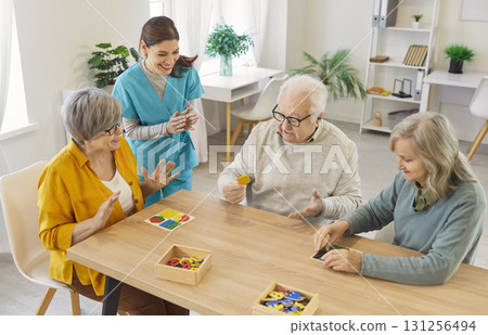 Elderly people solving puzzle with caregiver, enjoying mental stimulation and social interaction. 131256494