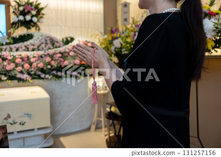 Hands of a young woman praying at a funeral home 131257156