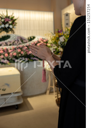 A young woman praying at a funeral parlor 131257254