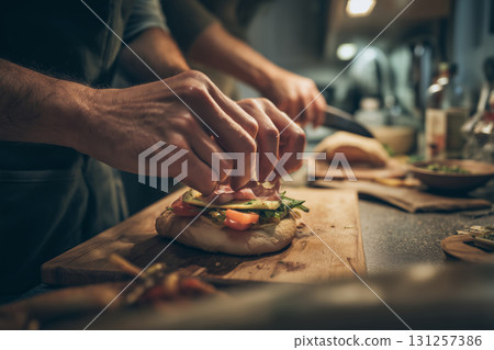 Hands creating delicious sandwiches in a cozy kitchen after sunset 131257386