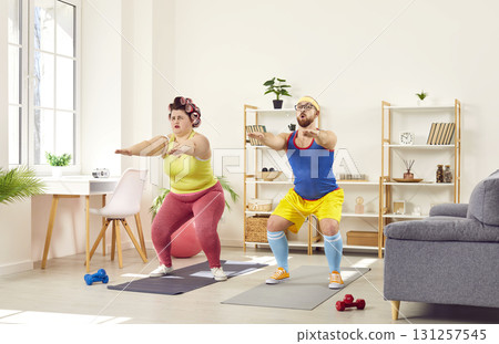 Funny family couple doing squat exercises together at home 131257545