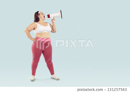 Young funny fat woman in sportswear screaming with mouthpiece on studio blue background. Young funny fat woman in sportswear screaming with mouthpiece on studio blue background. 131257563