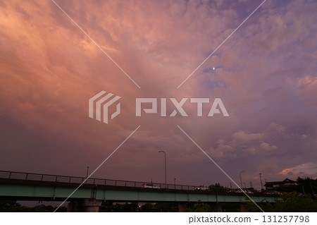 夕陽西下,半月漂浮在天空,橋樑輪廓清晰可見 夕陽西下,半月漂浮在天空,橋樑輪廓清晰可見 131257798