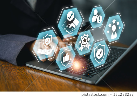 A business professional interacts with digital icons symbolizing trust and credibility on a laptop, highlighting modern technology's role. A business professional interacts with digital icons symbolizing trust and credibility on a laptop, highlighting modern technology's role. 131258252