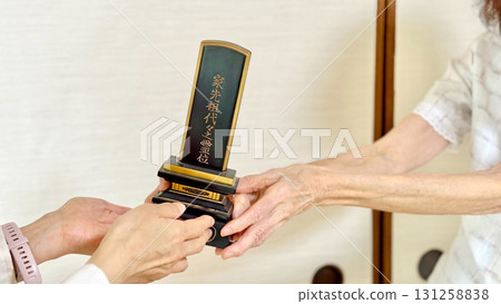 A woman's hand receiving a memorial tablet from an elderly woman_diagonal 131258838