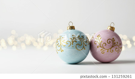 Two pastel Christmas ornaments (blue and pink) with gold swirl patterns on a clean white background with bokeh lights. Two pastel Christmas ornaments (blue and pink) with gold swirl patterns on a clean white background with bokeh lights. 131259261