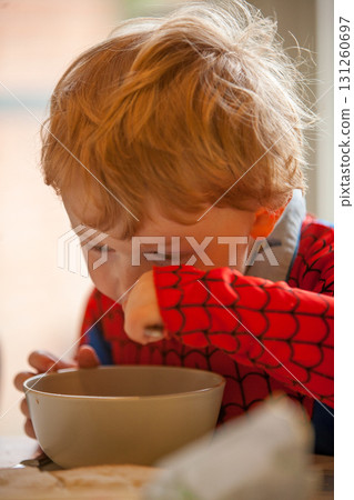 A Young Child Happily Enjoying Breakfast While Wearing a SpiderMan Styled Sweater A Young Child Happily Enjoying Breakfast While Wearing a SpiderMan Styled Sweater 131260697