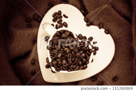Heart shaped cup with coffee beans on brown Heart shaped cup with coffee beans on brown 131260869