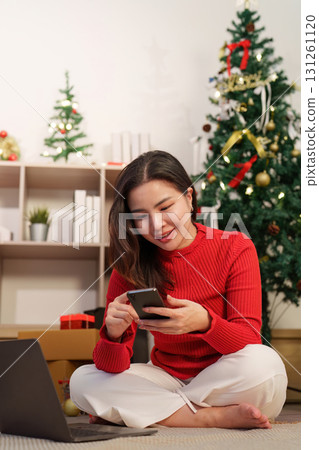 Christmas joy. Woman smiling while using smartphone for online shopping. 131261120