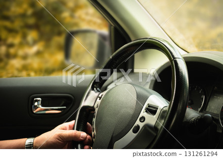 Male hands holding steering wheel in car, journey by car. Close up. 131261294