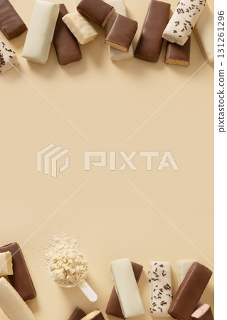 Frame of whey protein bars with various coatings and sprinkles scoop of protein powder on beige background. Healthy fitness nutrition. Banner. View from above. Copy space 131261296