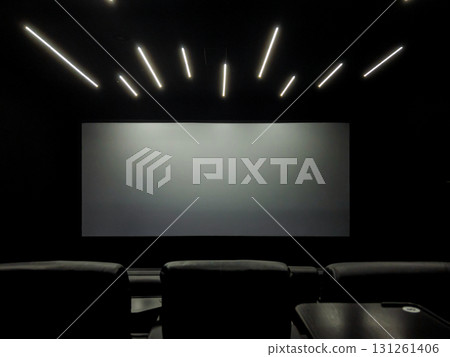 Blank cinema screen in a dark, modern movie theater, with comfortable seating and stylish linear ceiling lights, perfect for an immersive film or engaging business presentation Blank cinema screen in a dark, modern movie theater, with comfortable seating and stylish linear ceiling lights, perfect for an immersive film or engaging business presentation 131261406