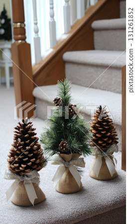 Three small evergreen trees in burlap bags sit on a staircase, adding a festive touch to the home during the holiday season Three small evergreen trees in burlap bags sit on a staircase, adding a festive touch to the home during the holiday season 131261852