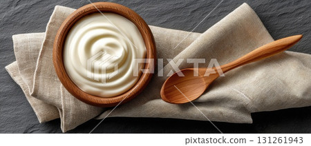 Creamy soup sits in a natural wooden bowl, topped with green herbs, alongside a wooden spoon on a checkered cloth Creamy soup sits in a natural wooden bowl, topped with green herbs, alongside a wooden spoon on a checkered cloth 131261943