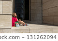 a happy fashionable young woman is relaxing in the sun on the background of a business center. 131262094
