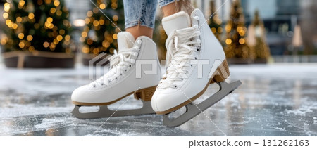 A skater enjoys a day on the ice, showcasing skill and elegance near a festive tree surrounded by a lively urban atmosphere 131262163