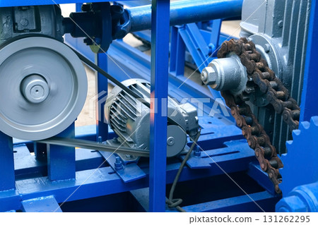 Engine of woodworking machine with chain rotating between gear wheels on plant. 131262295