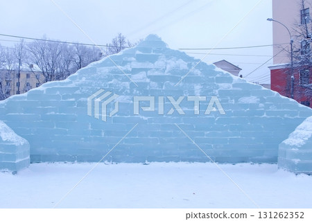 Ice brick wall in the town square. Decoration with ice figures for the holiday. Ice brick wall in the town square. Decoration with ice figures for the holiday. 131262352