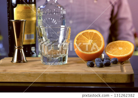 Barman prepares the ingredients for alcohol cocktail with tequila, Angostura bitter and fruits. Hands close-up. 131262382
