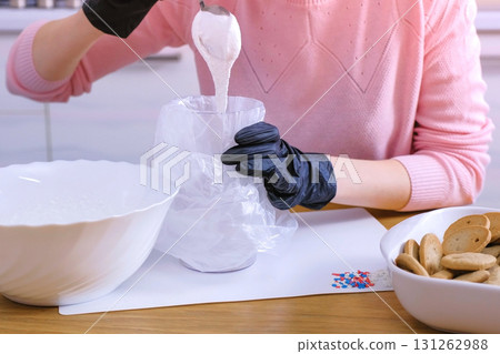 Woman's hands put the sugar sweet icing in the bag for decorating cookies and gingerbread houses. Woman's hands put the sugar sweet icing in the bag for decorating cookies and gingerbread houses. 131262988