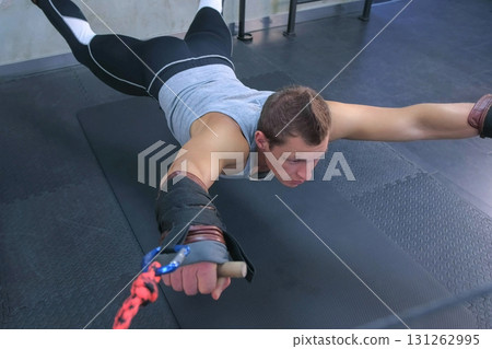 Sportsman training in air using trainer for myofascial stretching in gym. Sportsman training in air using trainer for myofascial stretching in gym. 131262995