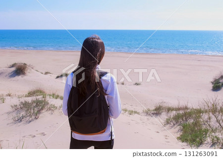 Girl travel stands on sand beach among dunes and look at sea vacation back view. Girl travel stands on sand beach among dunes and look at sea vacation back view. 131263091