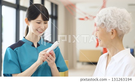 Asian caregiver taking the temperature of an elderly person 131263194