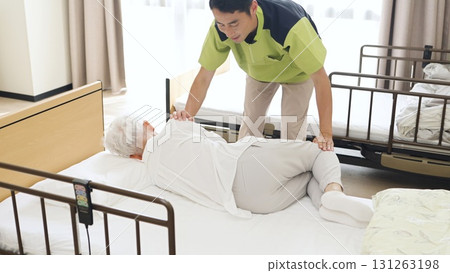 Asian caregiver changing the position of an elderly person Asian caregiver changing the position of an elderly person 131263198