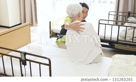 Asian caregiver changing the position of an elderly person Asian caregiver changing the position of an elderly person 131263201