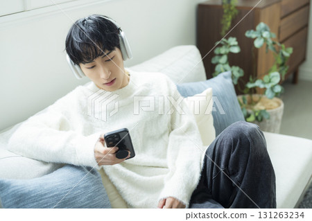 A man listening to music in the living room A man listening to music in the living room 131263234