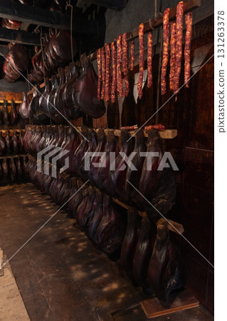 Interior scene of a dark meat smoking cellar with rows of hams and sausages Interior scene of a dark meat smoking cellar with rows of hams and sausages 131263378