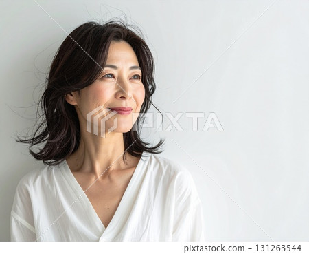 一位 40 多歲的日本女性身穿白襯衫，帶著溫柔的微笑 131263544