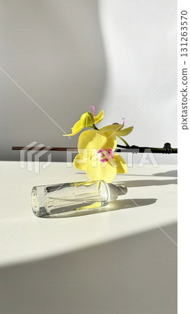 Glass cosmetic dropper with transparent facial serum and bottle on light background with orchid and natural sunlight. Beauty skincare product 131263570
