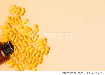 Scattered omega 3 softgels and amber bottle on warm beige copy space background 131263578